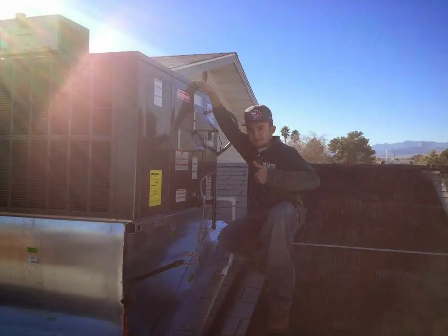 HVAC technician performing Boiler Repair on a rooftop unit in Livonia
